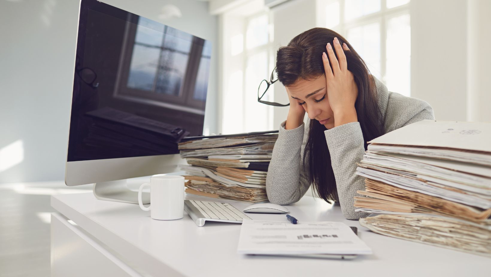 Stressed business woman with piles of documents around her.