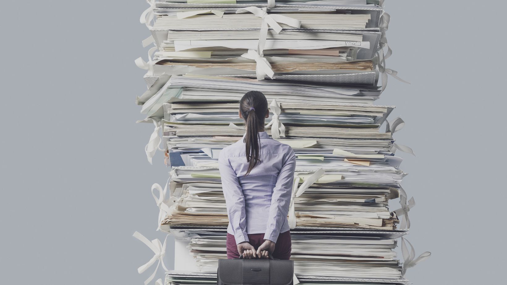 a business woman looking at a pile of documents bigger than her